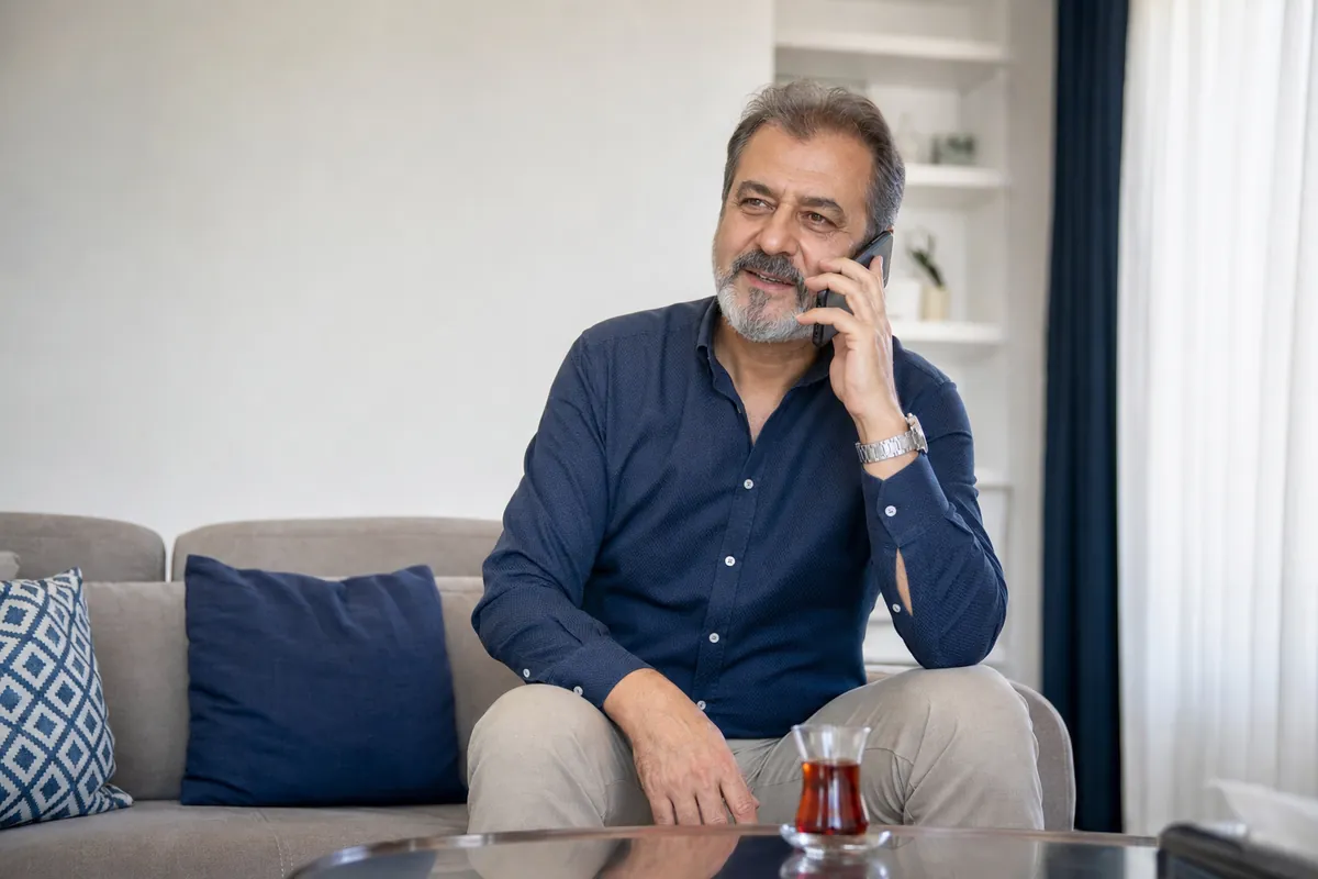Evinde koltukta oturup telefonla konuşan bir erkek
